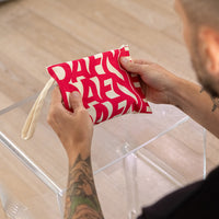Pochette Dafne in tessuto con stampa rossa su fondo naturale, tenuta in mano