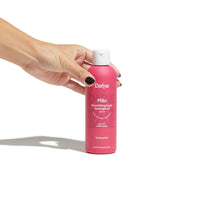 Olio massaggi Milo Dafne, neutro e naturale, in flacone magenta impugnato da una mano