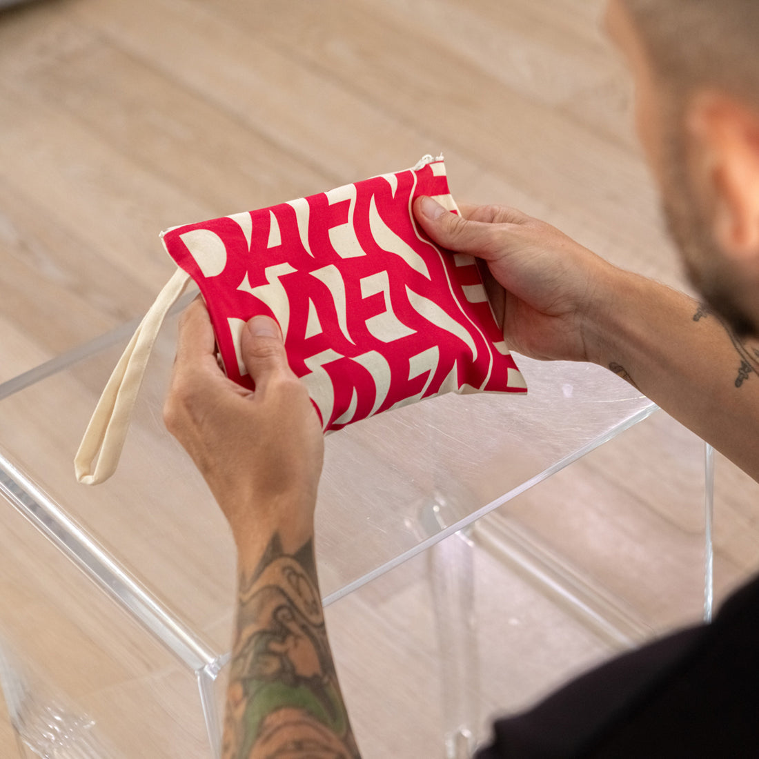 Pochette Dafne in tessuto con stampa rossa su fondo naturale, tenuta in mano