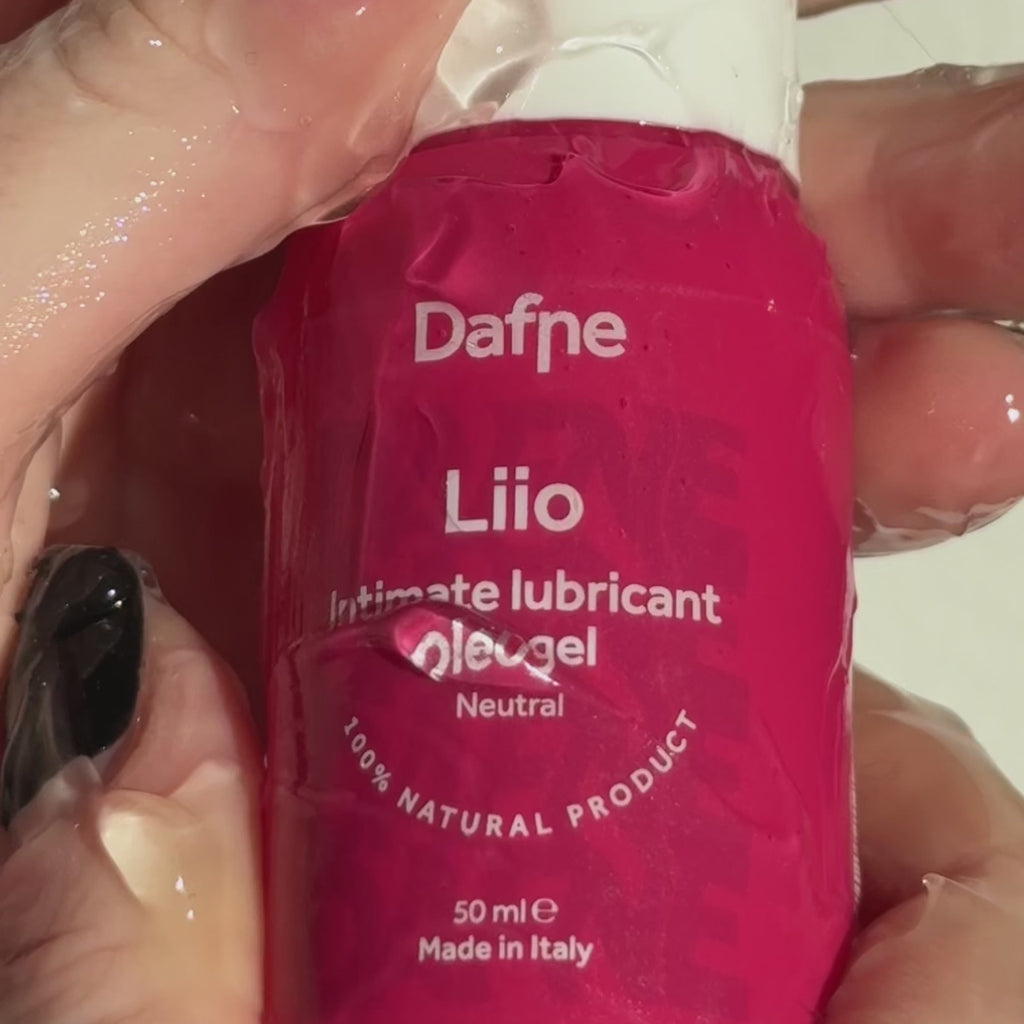 Video ravvicinato del lubrificante Liio Dafne, con mani ricoperte di prodotto che tengono il flacone, evidenziando la texture fluida