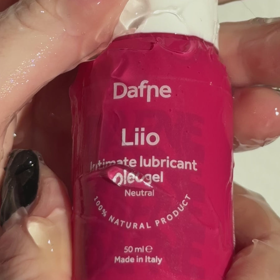 Video ravvicinato del lubrificante Liio Dafne, con mani ricoperte di prodotto che tengono il flacone, evidenziando la texture fluida